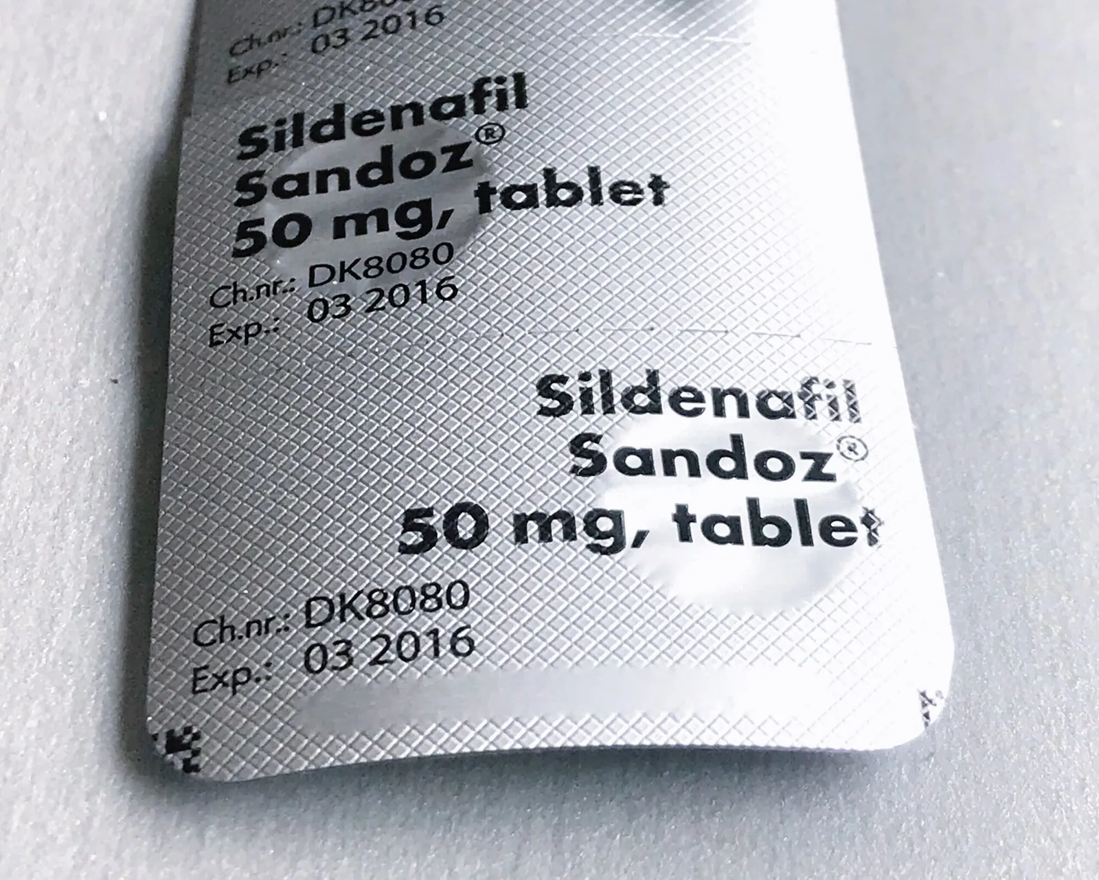 Compressa di sildenafil equivalente da 50 mg accanto alla sua confezione